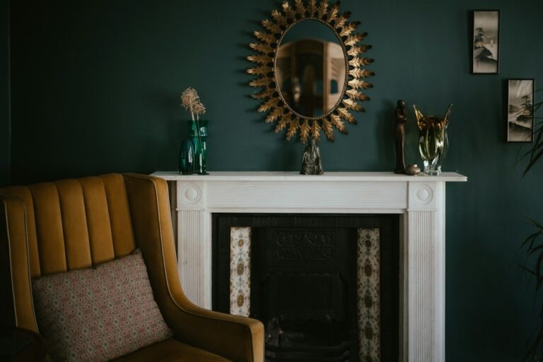 A mirror above a fireplace beside an armchair.